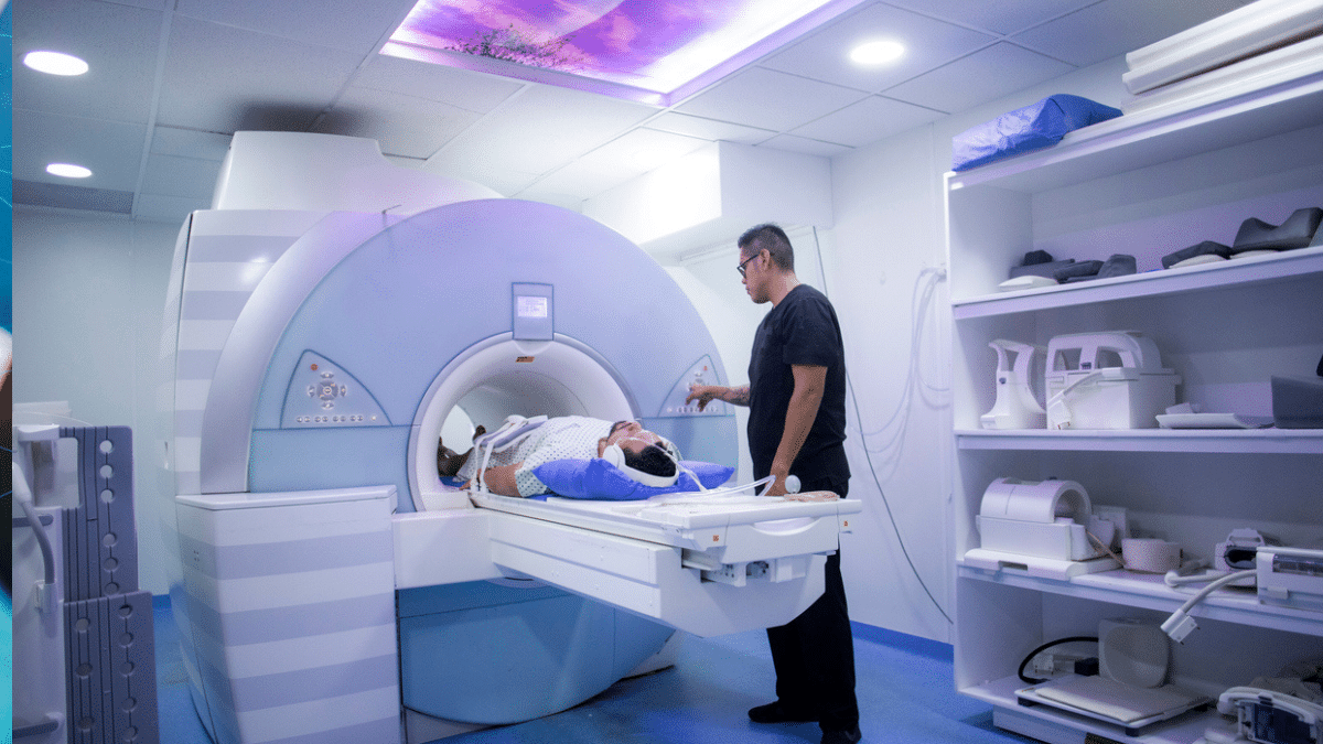 Stock photo of a patient in an MRI machine with a technician pressing buttons.