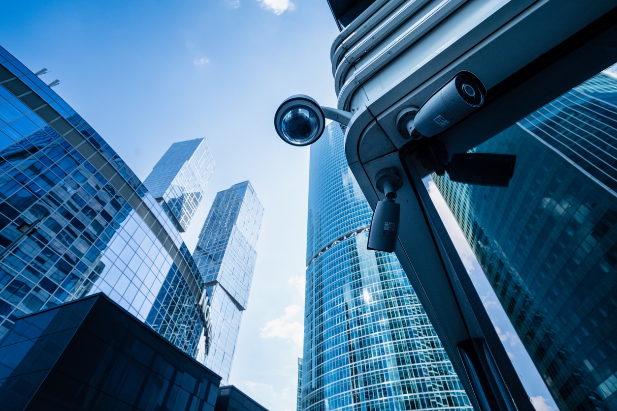 Security camera on a business building corner, modern skyscrapers at the background